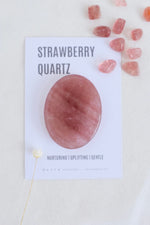 Strawberry quartz stone with a card displaying text on a light background