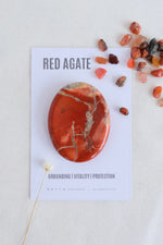 Red agate stone on a card with text on a light gray background