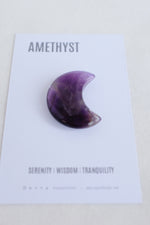 Purple moon-shaped crystal on card