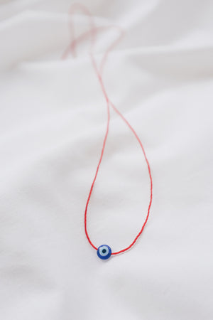 Evil eye pendant necklace on red string, symbolizing protection and warding off negative energy.