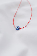 Evil eye pendant necklace on red string, symbolizing protection and warding off negative energy.