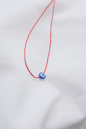 Evil eye pendant necklace on red string, symbolizing protection and warding off negative energy.