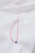 Evil eye pendant necklace on red string, symbolizing protection and warding off negative energy.