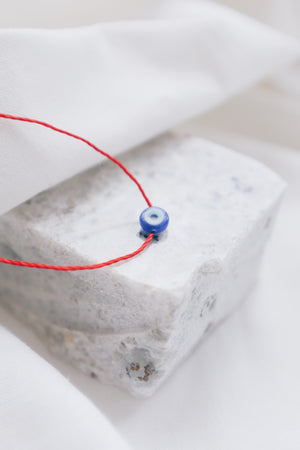 Evil eye pendant necklace on red string, symbolizing protection and warding off negative energy.