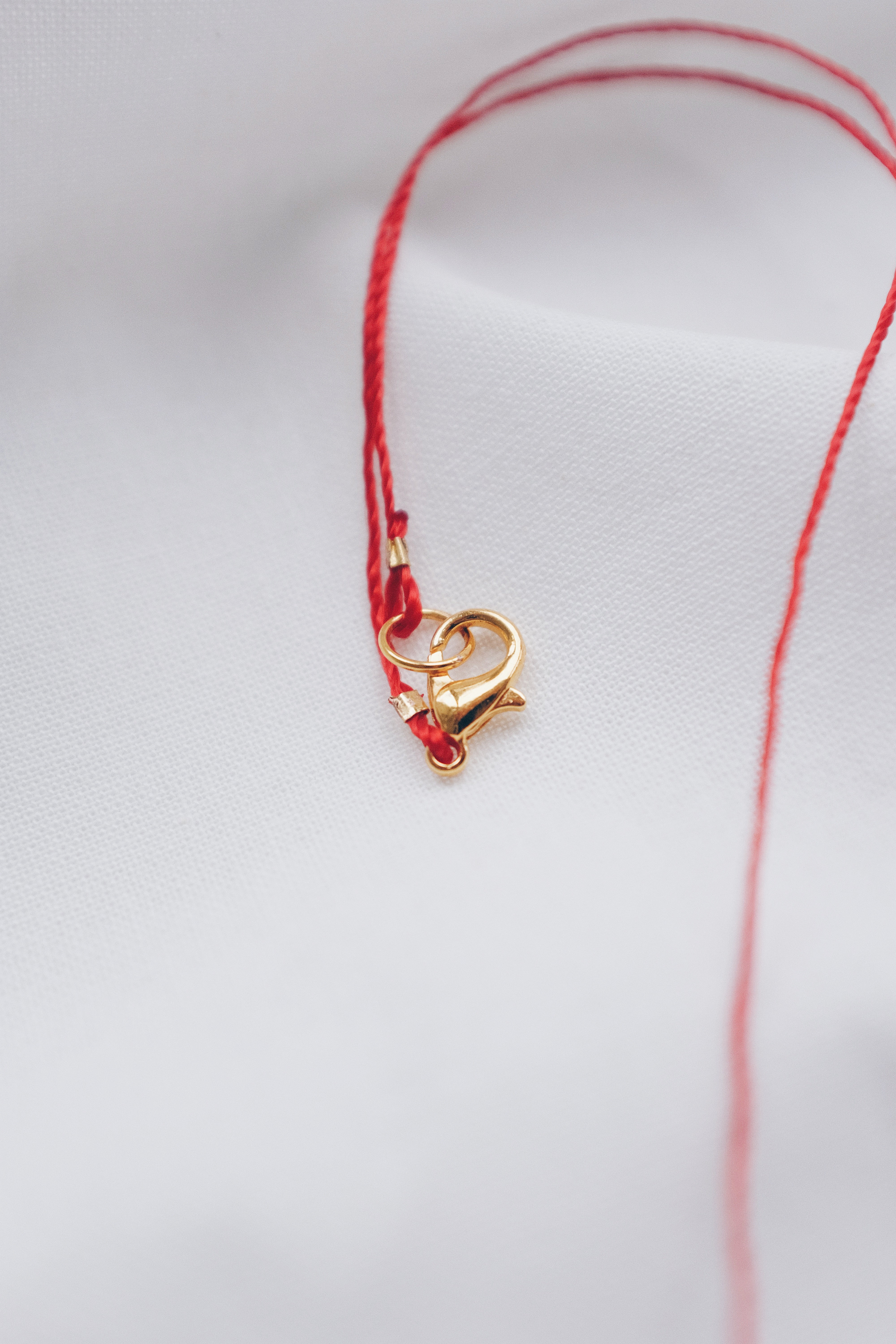 Gold fish pendant on a red string necklace, symbolizing luck and abundance.