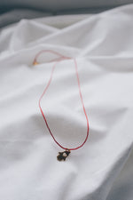 Gold hamsa hand pendant on red string necklace, symbolizing protection and blessings.