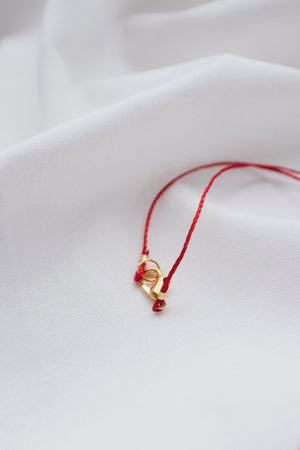 Gold hamsa hand pendant on red string necklace, symbolizing protection and blessings.