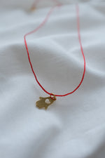 Gold hamsa hand pendant on red string necklace, symbolizing protection and blessings.