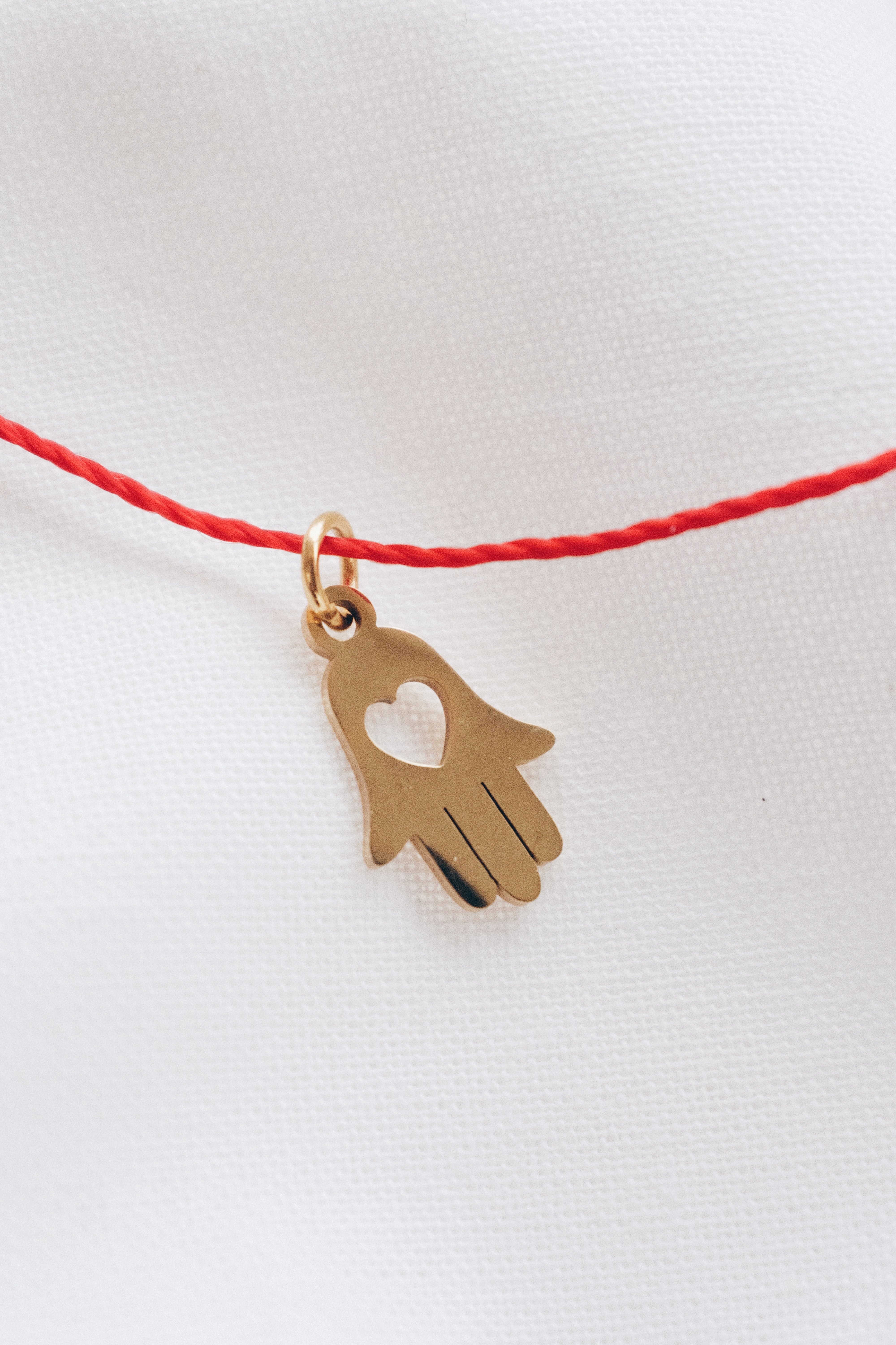 Gold hamsa hand pendant on red string necklace, symbolizing protection and blessings.