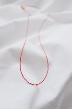 Gold tube red string protection bracelet on wrist