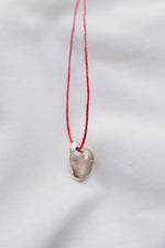 Pearl pendant on a red string necklace, classic and elegant jewelry piece.