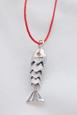 Silver fish pendant on a red string necklace, symbolizing luck and abundance.