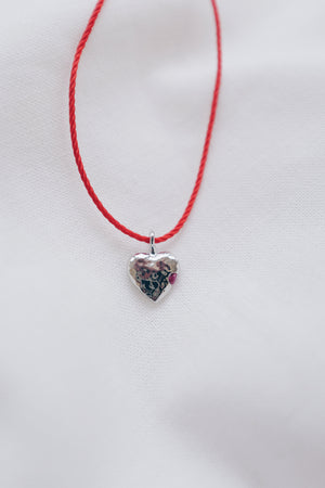 Silver ruby pendant on a red string necklace, elegant and vibrant gemstone jewelry.