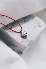 Silver ruby pendant on a red string necklace, elegant and vibrant gemstone jewelry.