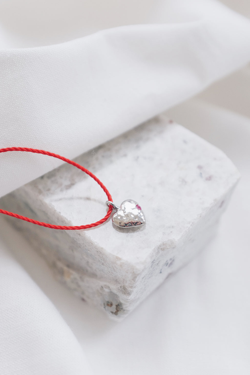 Silver ruby pendant on a red string necklace, elegant and vibrant gemstone jewelry.