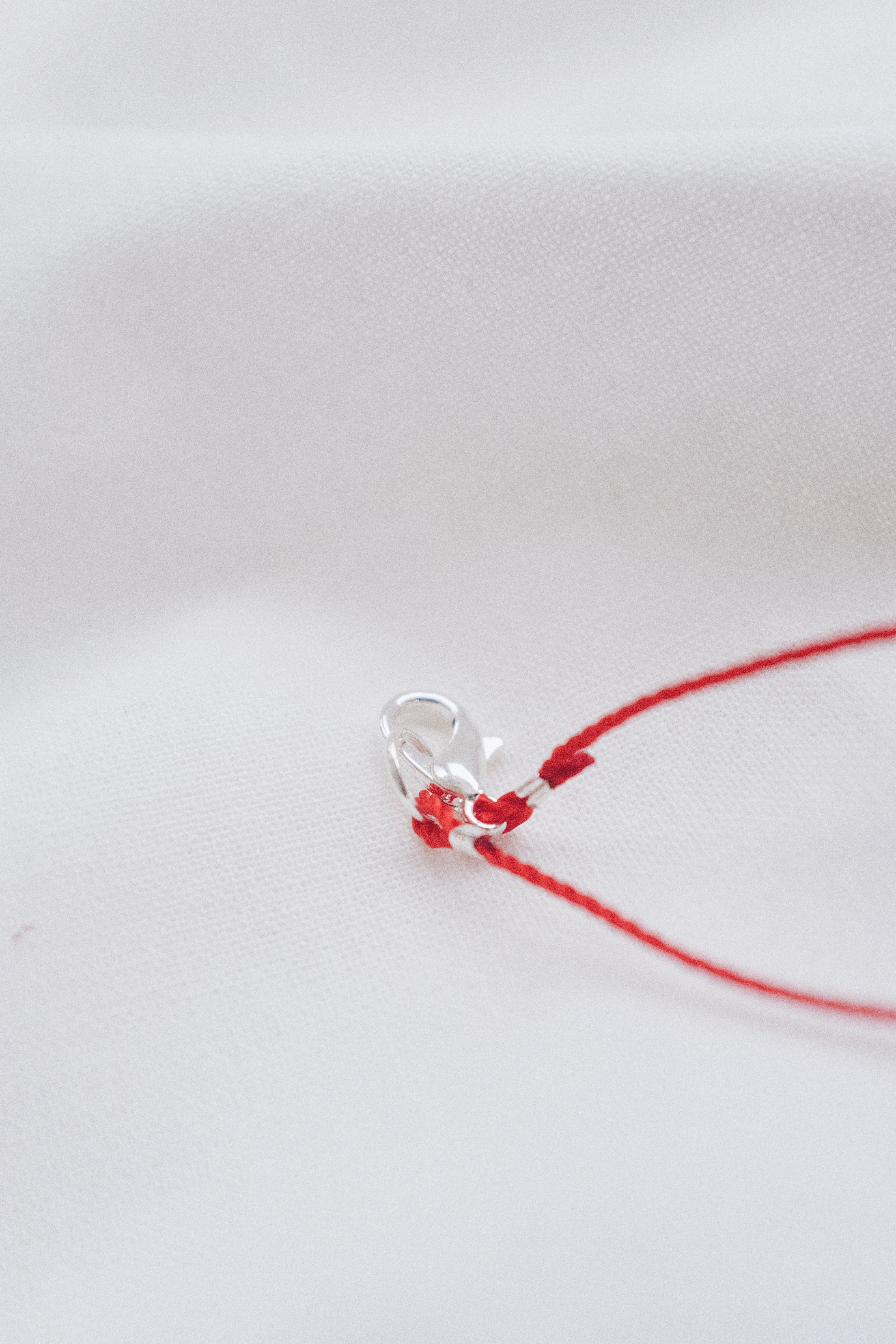 Silver tube pendant on a red string necklace, minimalist and stylish jewelry.